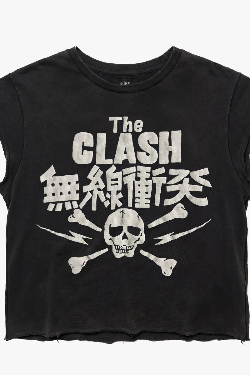 A black cropped sleeveless t-shirt featuring a distressed white graphic print of 'The Clash' skull and crossbones logo with Japanese characters, displayed flat against a light gray background.