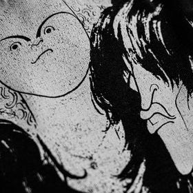 Black and white close-up graphic print featuring stylized illustrated faces, likely from a band t-shirt design.